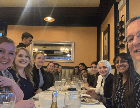 Aron, on the right, and Lauren Sellers, MS2, on the left, have a Turkish dinner with the assembled students and faculty of the 2024 Chicago Immersion Trip.
