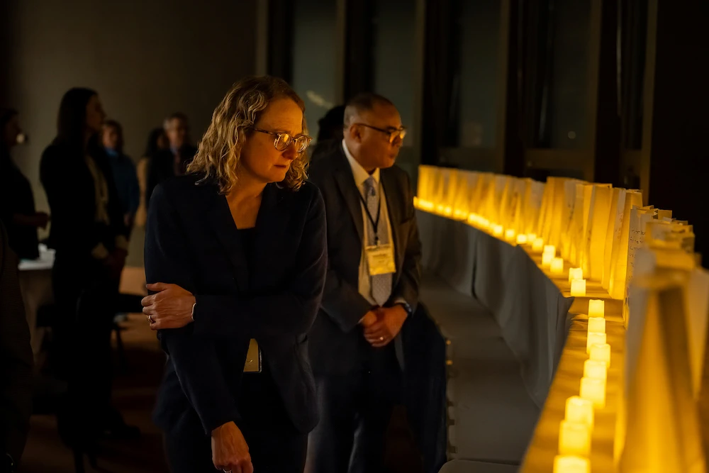  Andrea Wendling, along with conference participants, walk past luminaries during the remembrance ceremony to conclude the first night. Photo credit Bryan Esler.